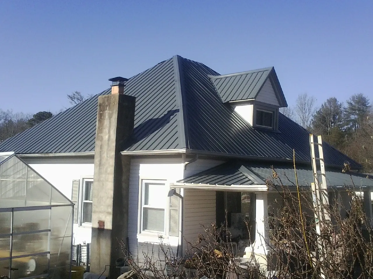 Dark blue standing seam metal roof on a white farmhouse with dormer — Slate & Tile Roof Repair by Roofing Brothers in Poestenkill