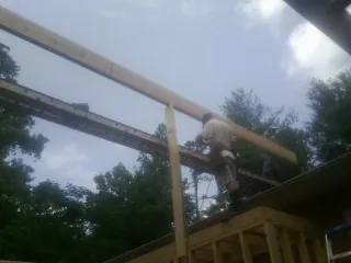 Carpenter setting a ridge beam over a new addition frame — Ice Dam Removal by Roofing Brothers in Poestenkill