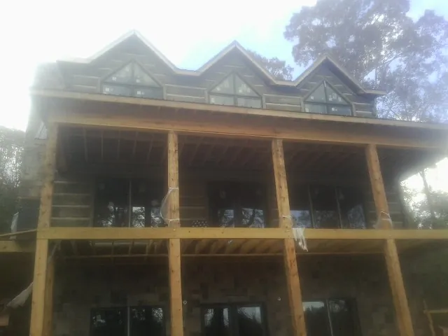 Dormers and porch framing on a large log home under construction — Roof Coating work by our crew in Poestenkill