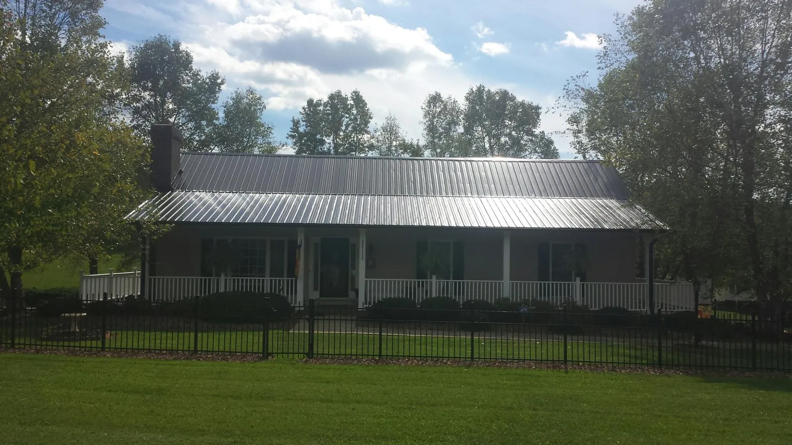 Gray metal roof on a brick ranch with a full width front porch — Gutter Guard Installation work by our crew in Poestenkill
