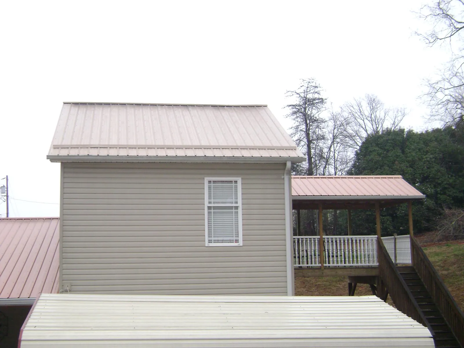 Tan metal roofs on a two story addition and attached porch, from a Roof Replacement job in Poestenkill