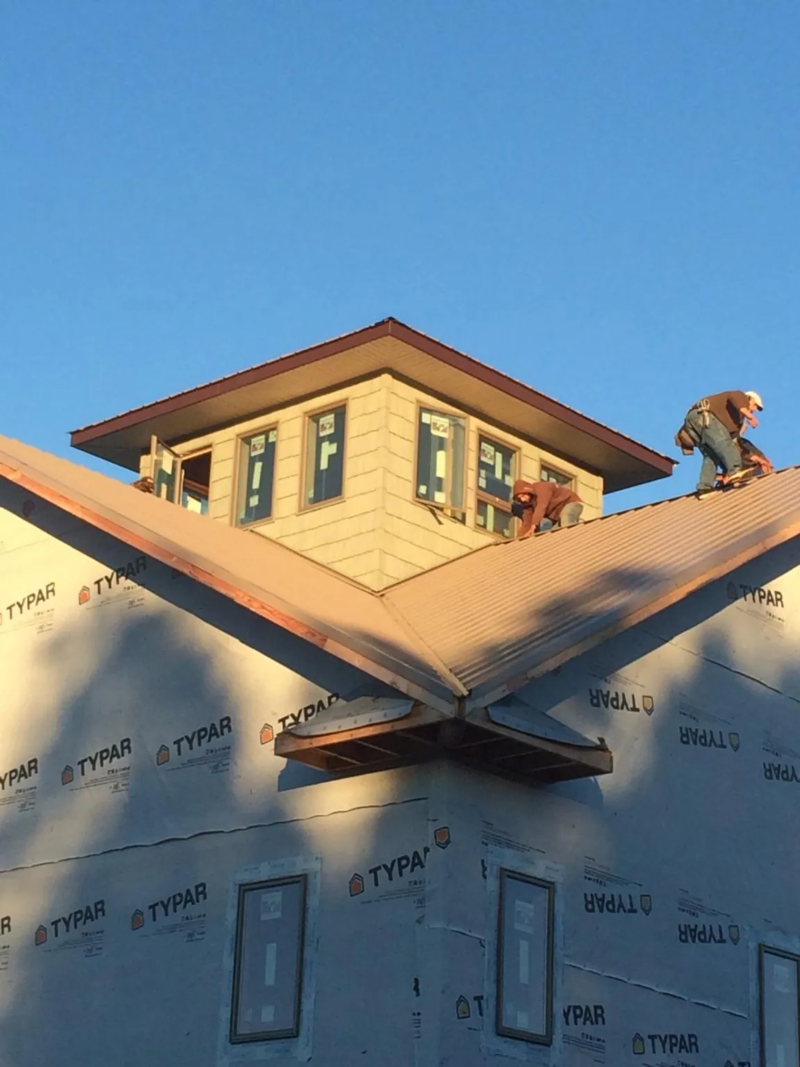 Roofers working around a rooftop cupola on a new metal roof at sunset — Roof Waterproofing in Poestenkill by Roofing Brothers
